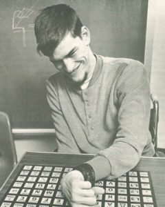 A man who uses a wheelchair is touching keys on a modified keyboard