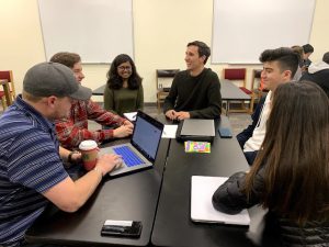 A group of six students sitting at a table together, laughing and talking.